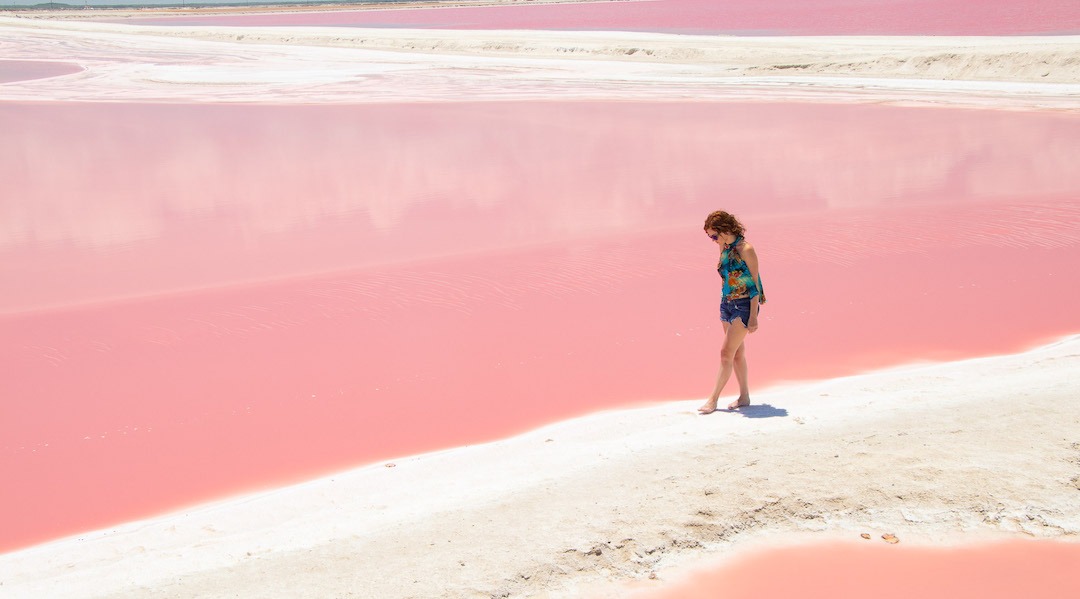 Mujer caminando junto al lago rosa en las coloradas Yucatan