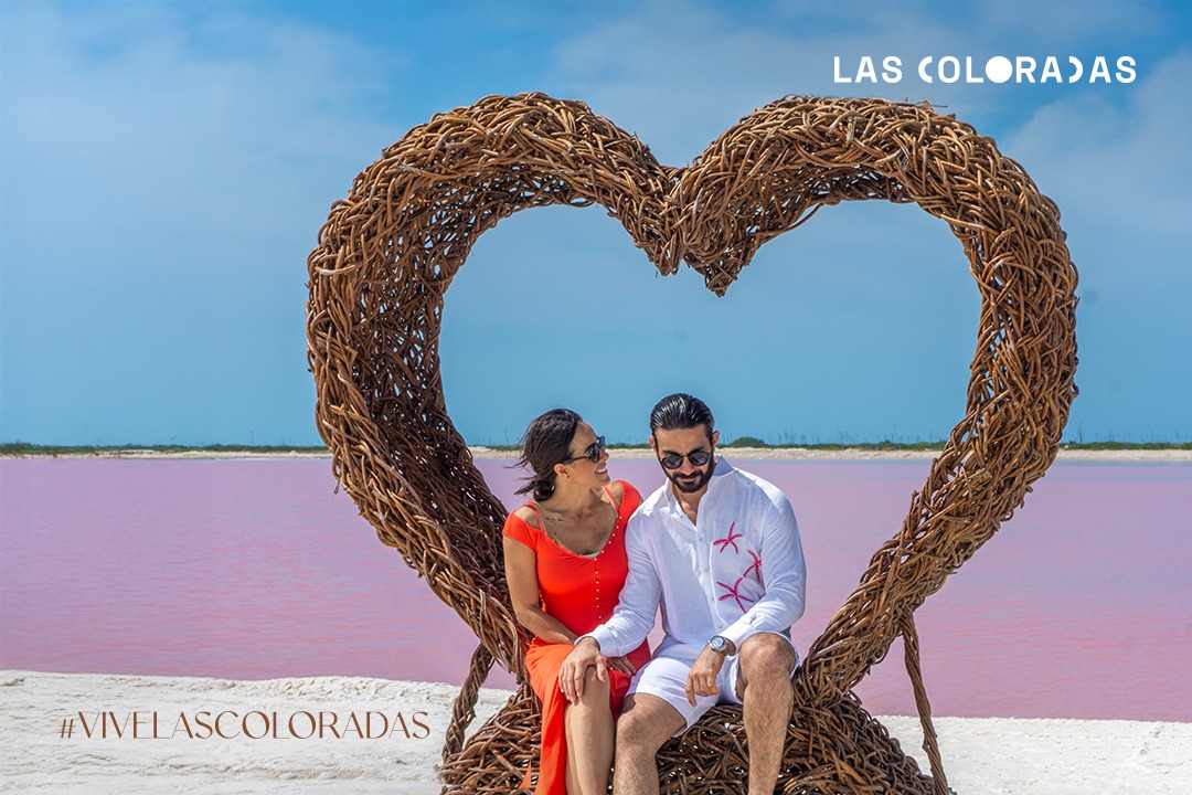 Pareja disfrutando de un paseo en Las Coloradas, con las lagunas rosas de fondo.